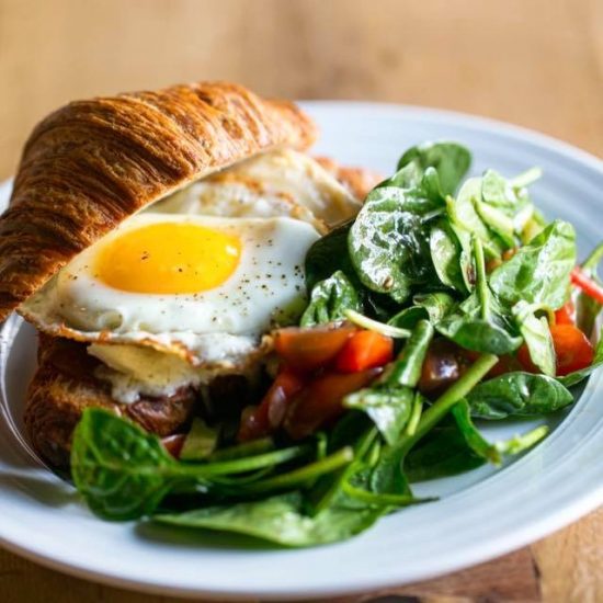 Runny Egg Croissant Sandwich and Dressed Greens